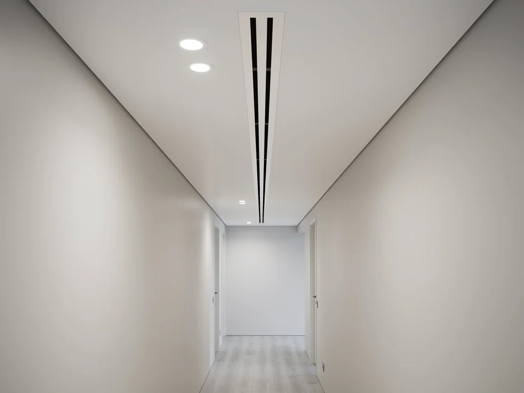 Grille de diffusion gainable intégrée au plafond d'un couloir contemporain
